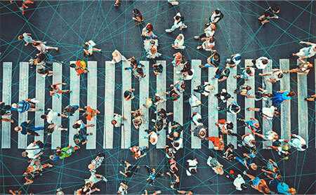 Aerial view of a crowd walking within a crosswalk with blue lines overlay illustrating people connected by a network