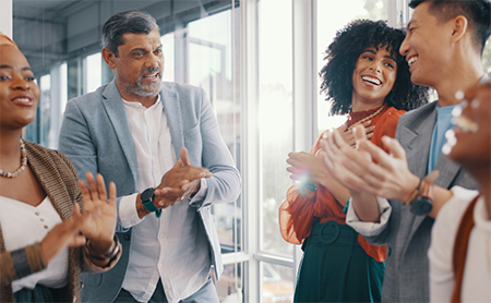 A diverse group of coworkers talks and laughs in an office