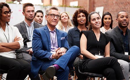 An engaged, diverse audience listens to an out-of-frame speaker