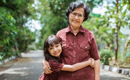 Asian granddaughter hugging her grandmother outside in a park