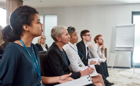 A diverse group of professionals listening to an out-of-frame speaker