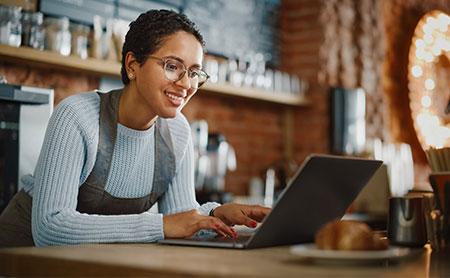 Latina coffee shop owner working on a laptop in a cafe.