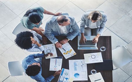 Overhead view of people at a conference table discussing data and analytics