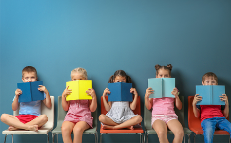 Seated kids peeking over the top of their books