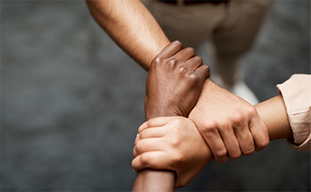 Three men use their right hands to grip another's wrist, creating a strong triangle