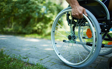 Wheelchair, moved forward under user's own power, moving along a park path.