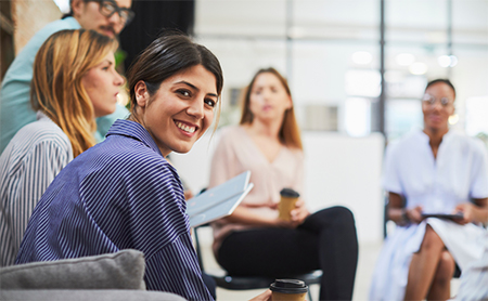 A woman in a meeting looks over her shoulder and smiles